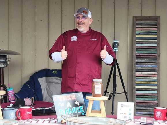 A man is giving a thumbs up while standing in front of a table.