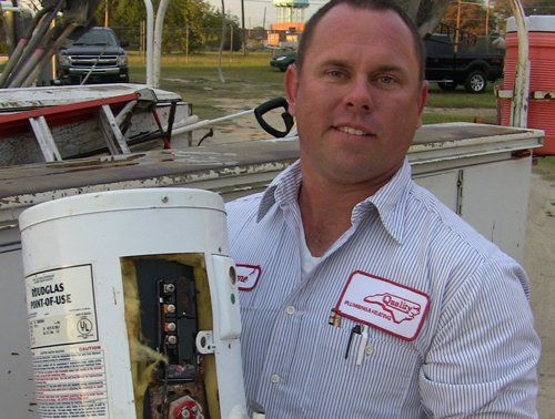 Man Holding Tankless Water Heater — Goldsboro, NC — Quality Plumbing & Heating Co.