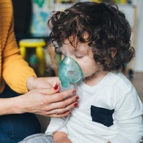 Child receiving nebulizer treatment with assistance.