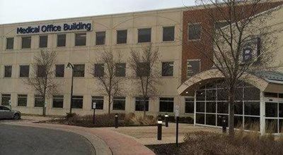 Medical office building with beige facade, windows, and arched entrance.