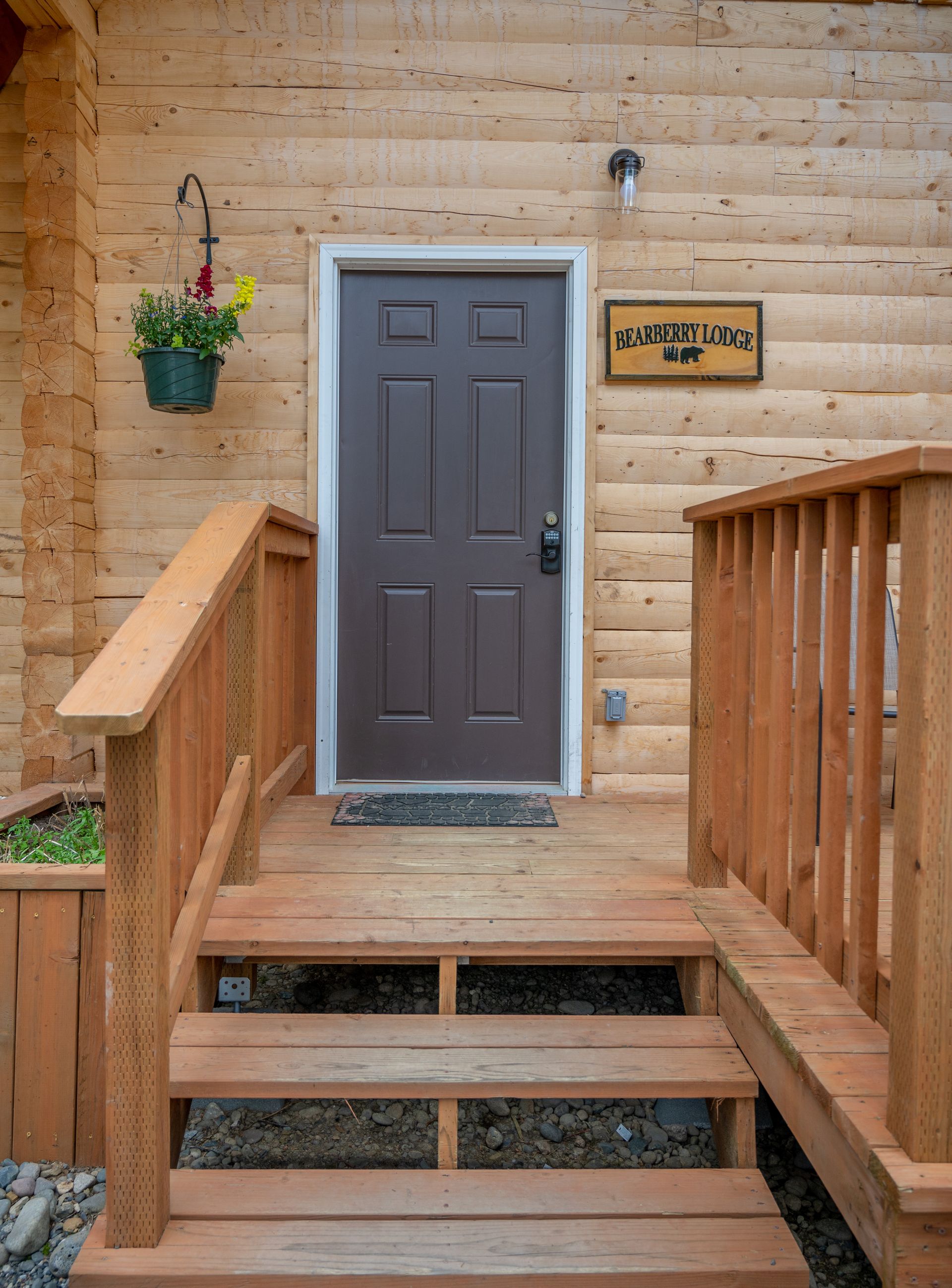 Bedroom with wooden walls, a red bedspread, and a bear-themed throw blanket.