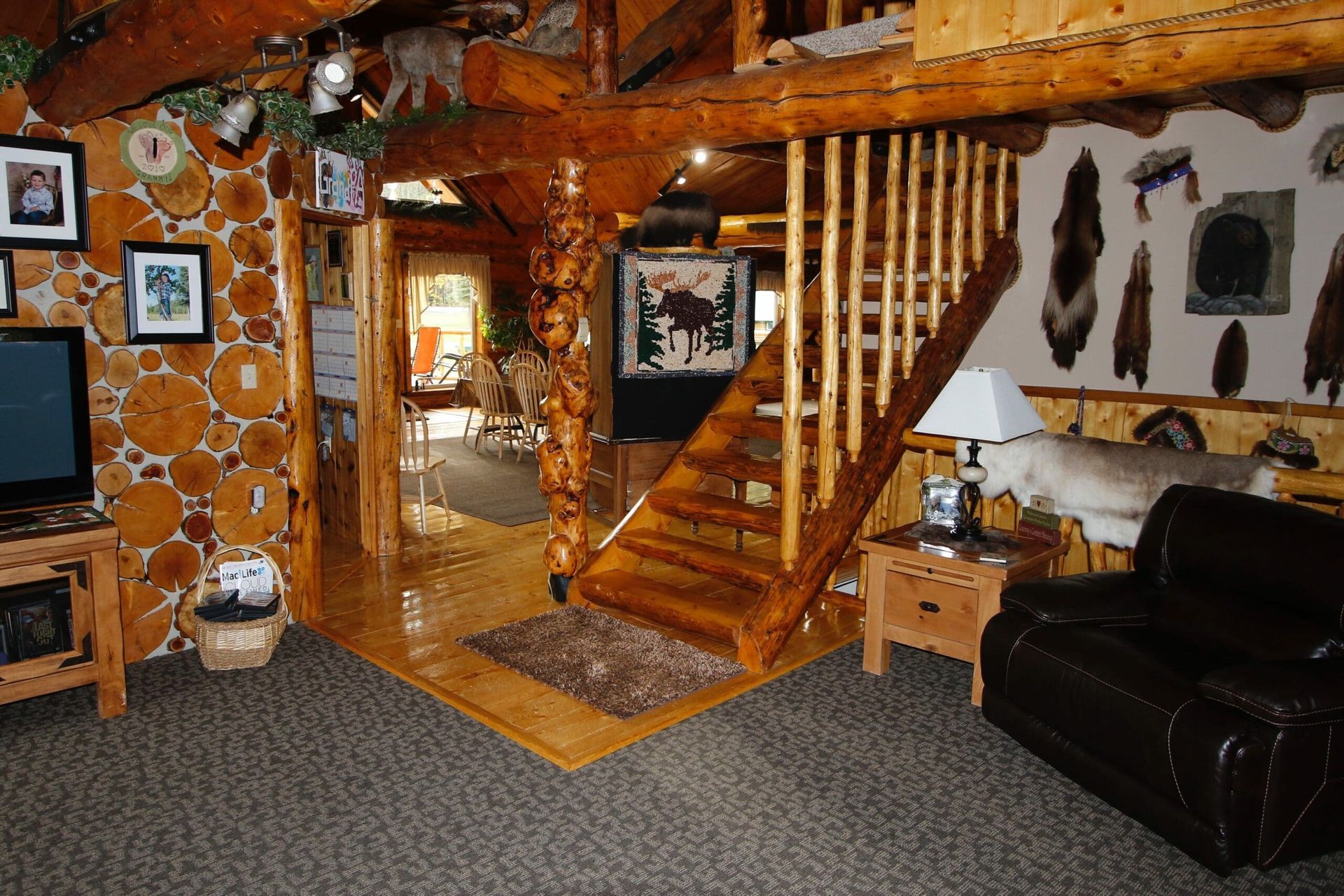 A living room in a log cabin with stairs leading up to the second floor