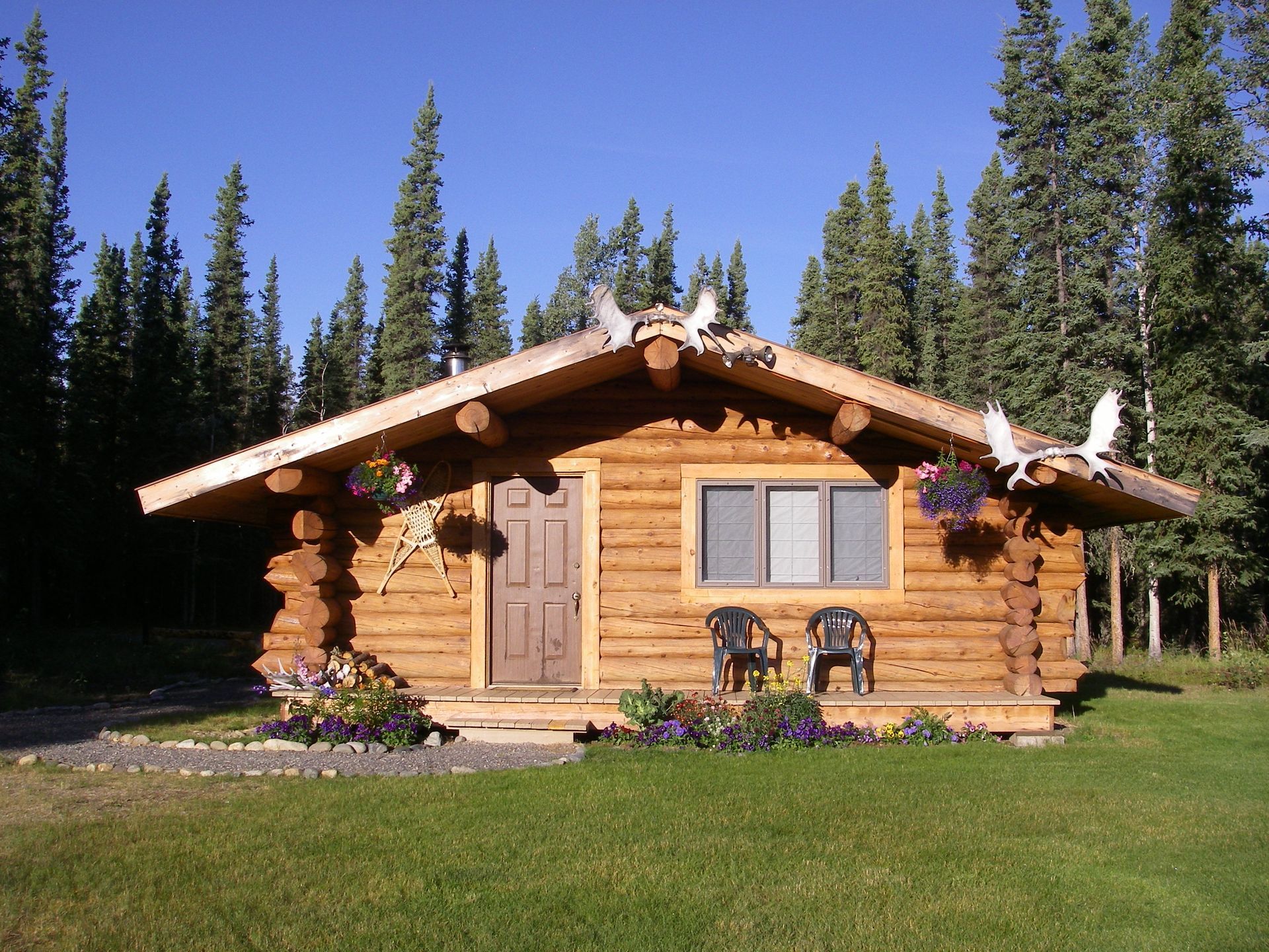 An aerial view of a house in the middle of a forest with mountains in the background.