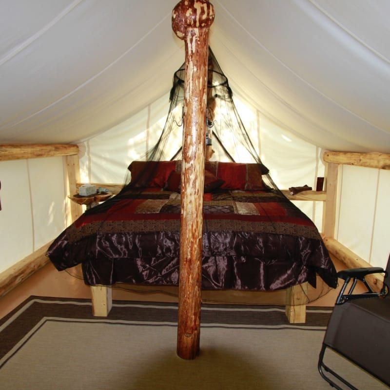 A bed in a tent with a wooden post in the middle