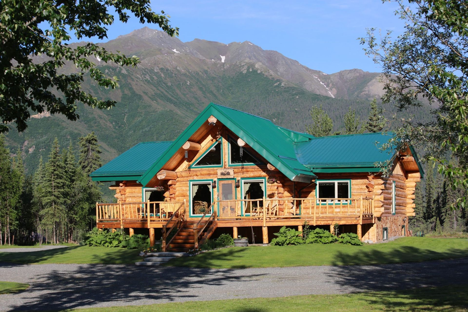 A log cabin with a green roof and mountains in the background