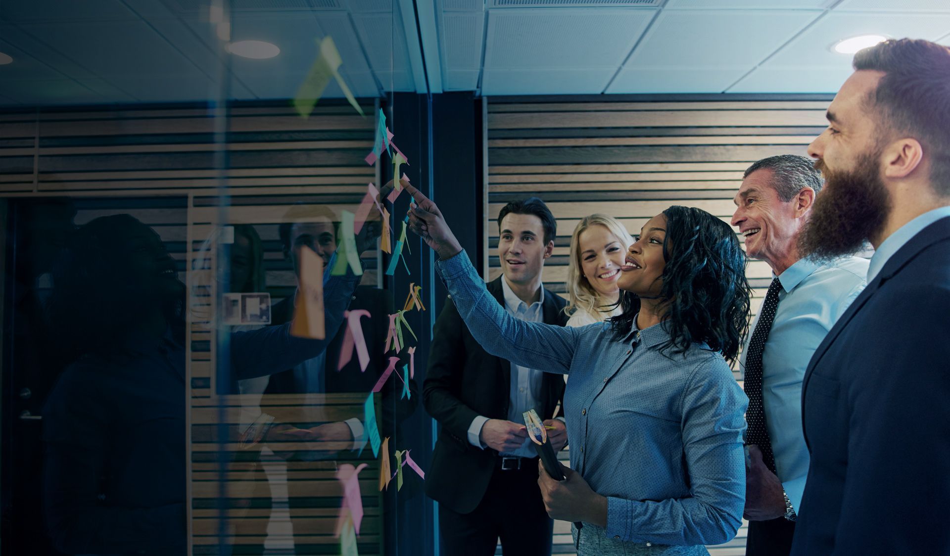 a group of business people are looking at sticky notes on a glass wall .