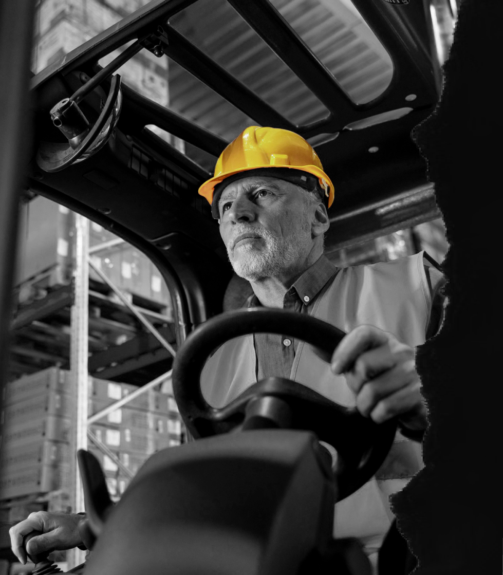 Un hombre conduce una carretilla elevadora Caterpillar amarilla al aire libre en un día soleado.