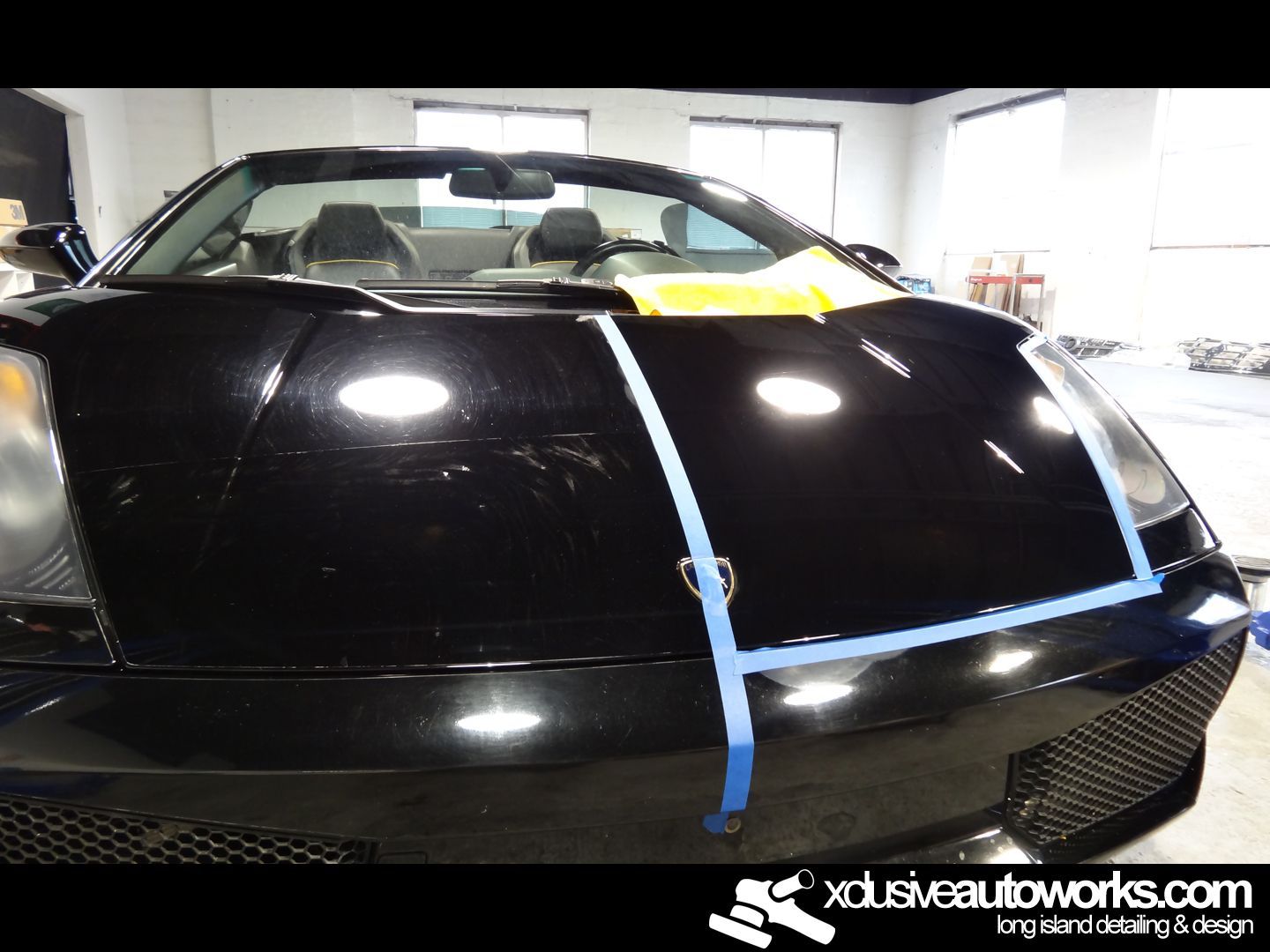 A black sports car with a blue tape around the hood