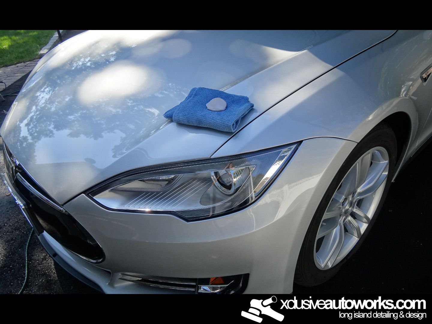 A tesla model s with a blue cloth on the hood