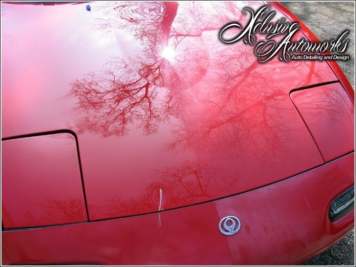A close up of a red car 's hood with a logo on it