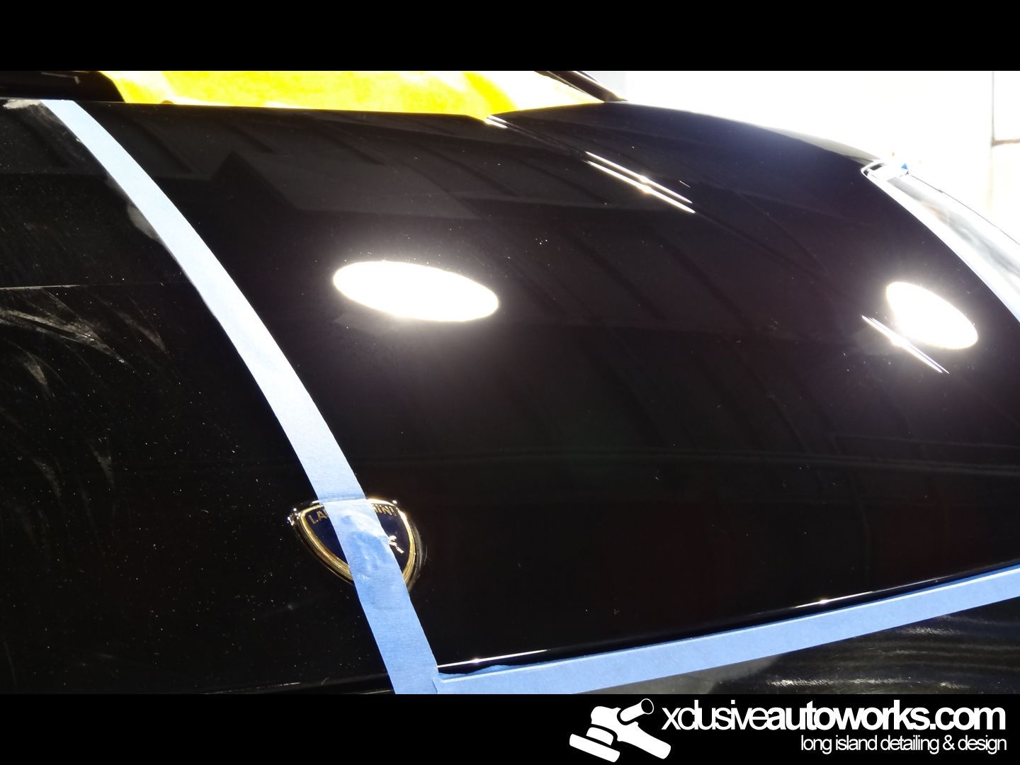 A black car is being polished by xclusiveautoworks.com