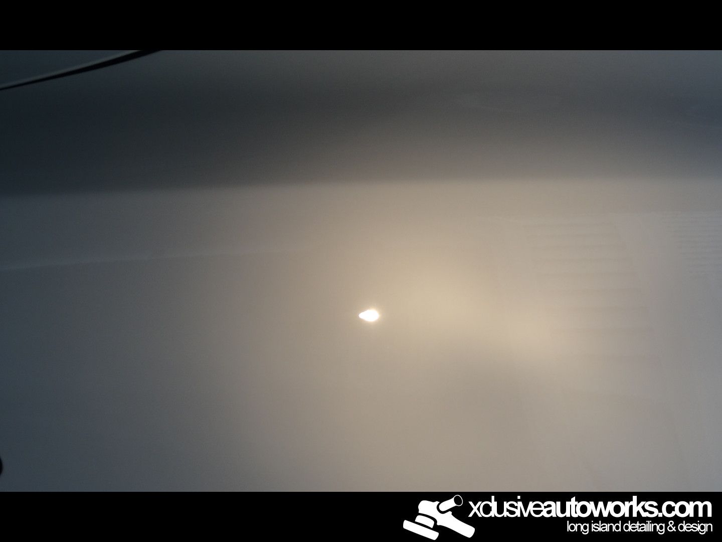 A close up of a car hood with xclusiveautoworks.com written on the bottom