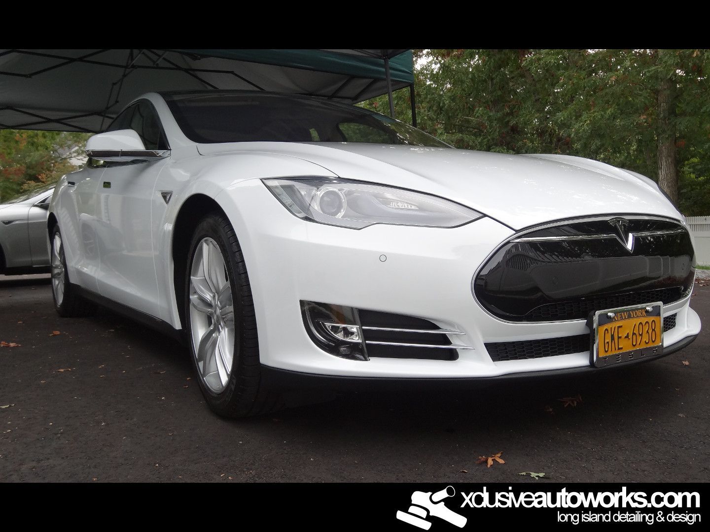 A white tesla model s is parked under a tent