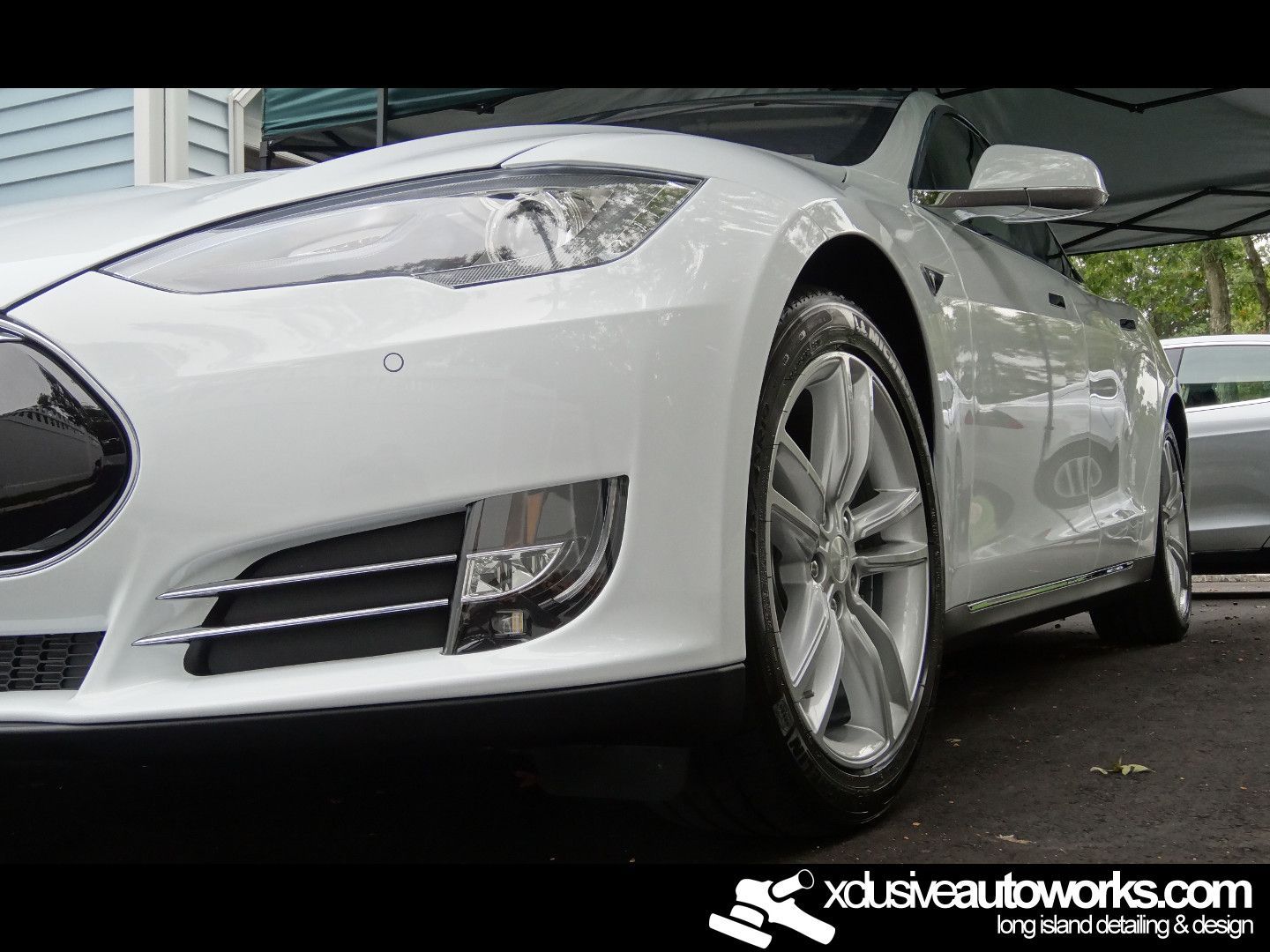 A white tesla model s is parked in front of a house.