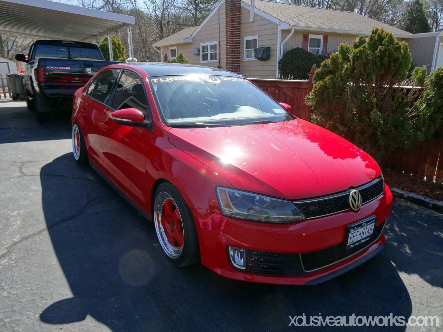 A red volkswagen jetta is parked in front of a house