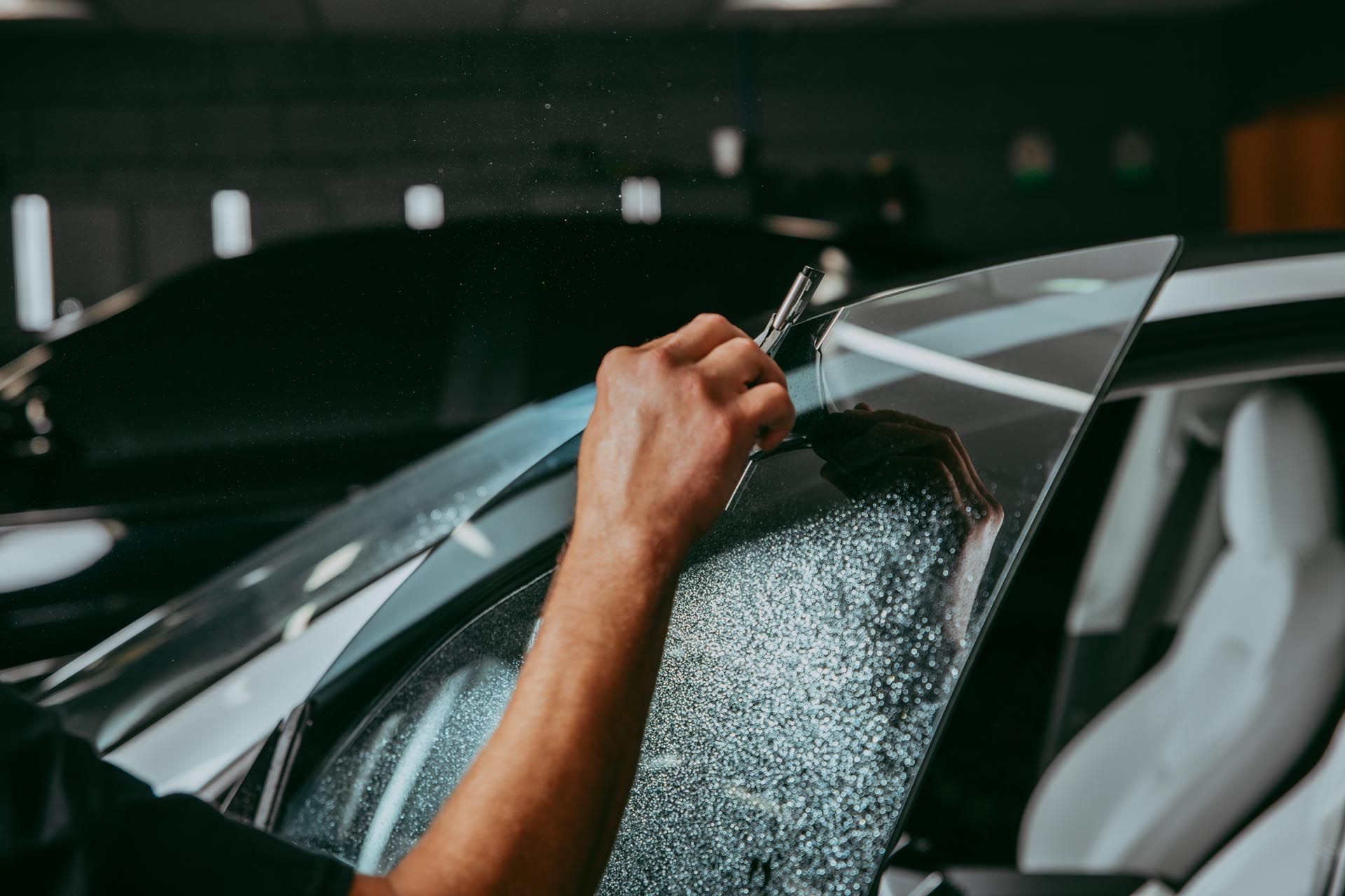 A person is applying tinted glass to a car window.