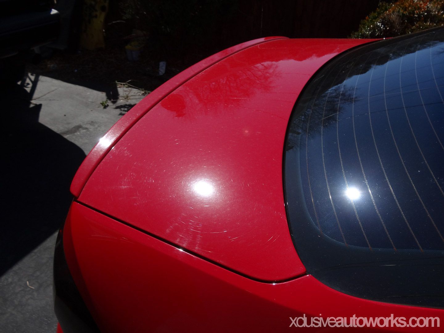 A red car with the website xclusiveautoworks.com in the corner