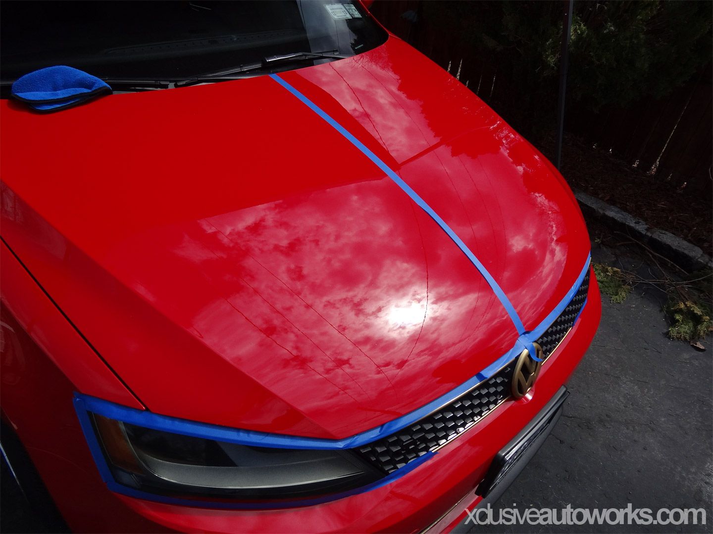 A red car with exclusiveautoworks.com written on the bottom