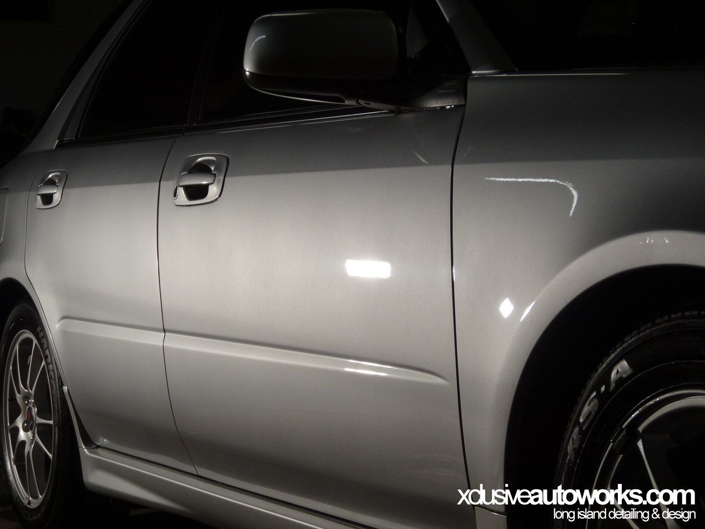 A silver car with the website xdusveautoworks.com on the bottom