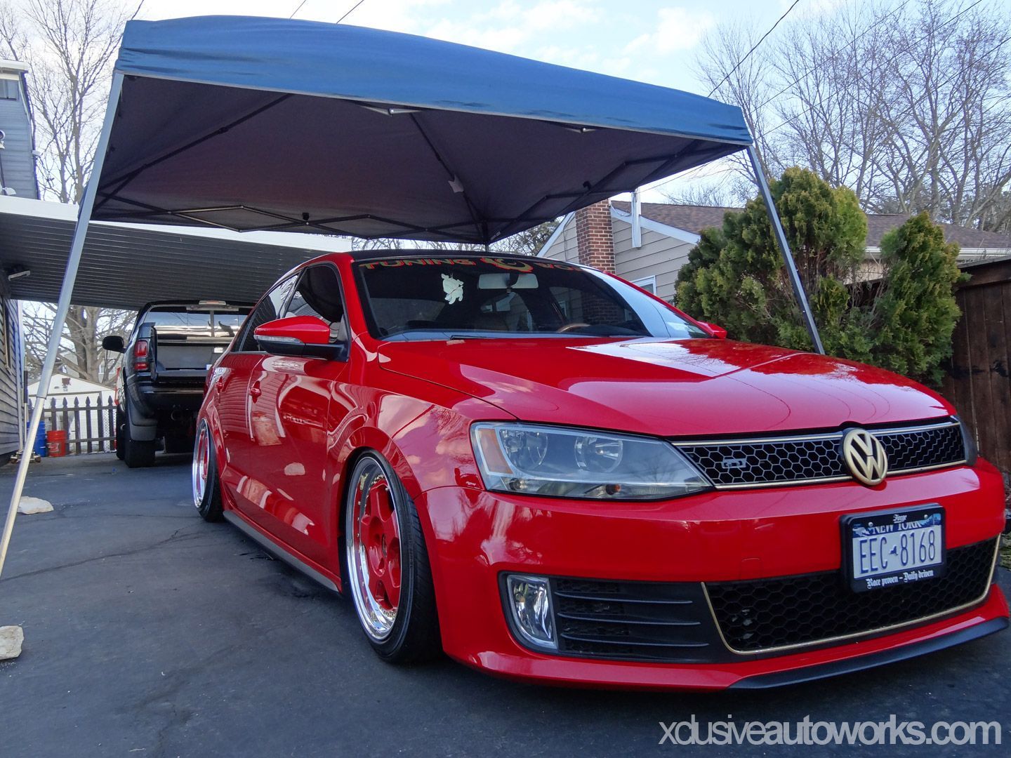 A red volkswagen jetta is parked under a blue canopy