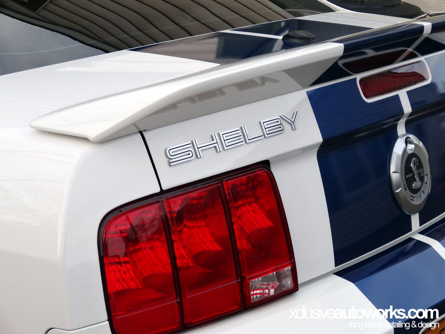 A blue and white shelby mustang with a spoiler