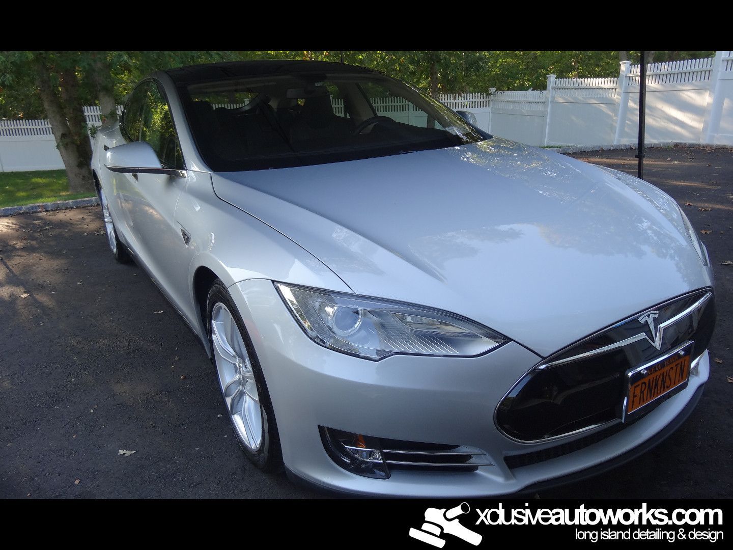 A silver tesla model s is parked in a driveway
