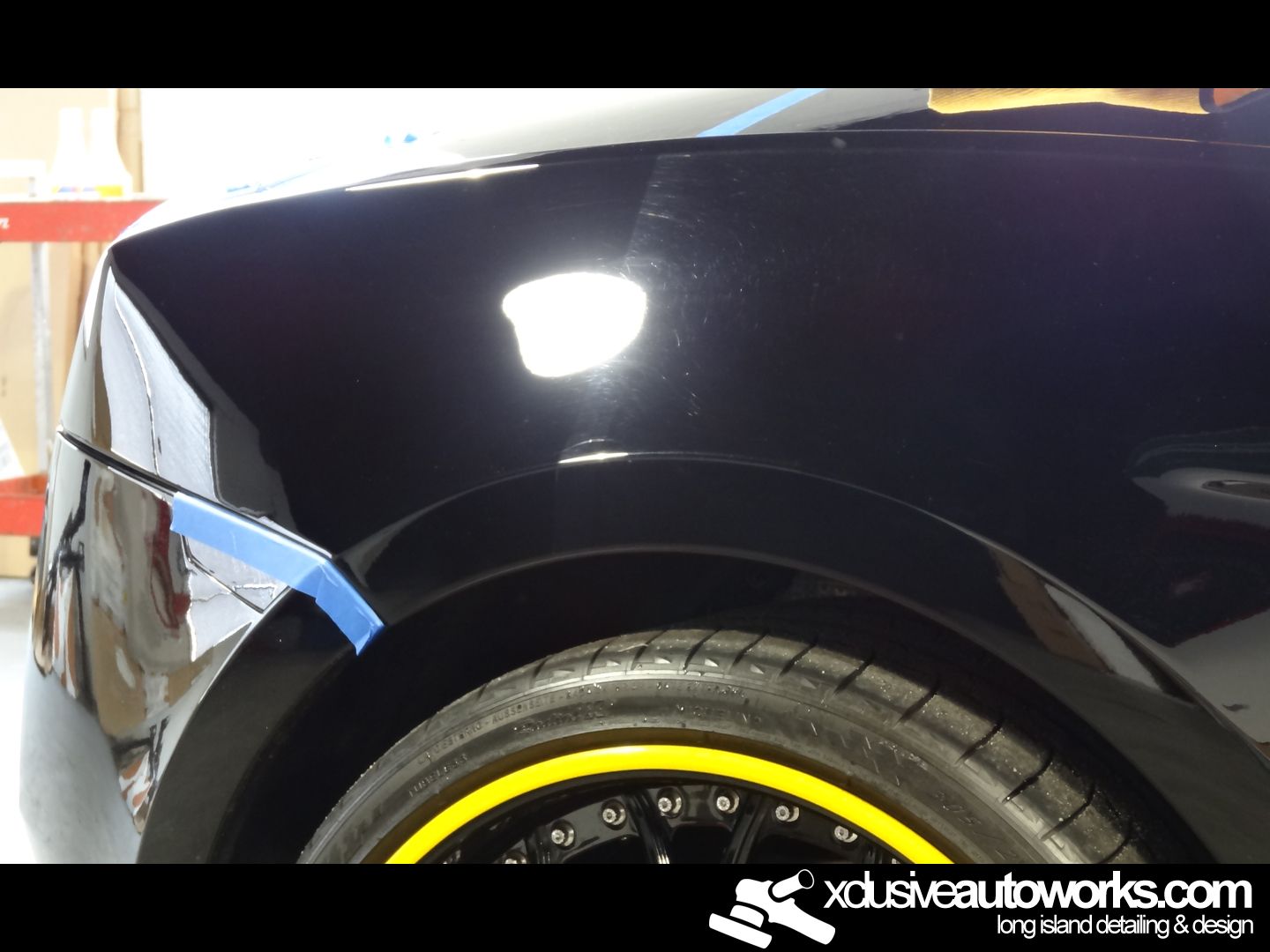 A close up of a black car with xclusiveautoworks.com written on the bottom