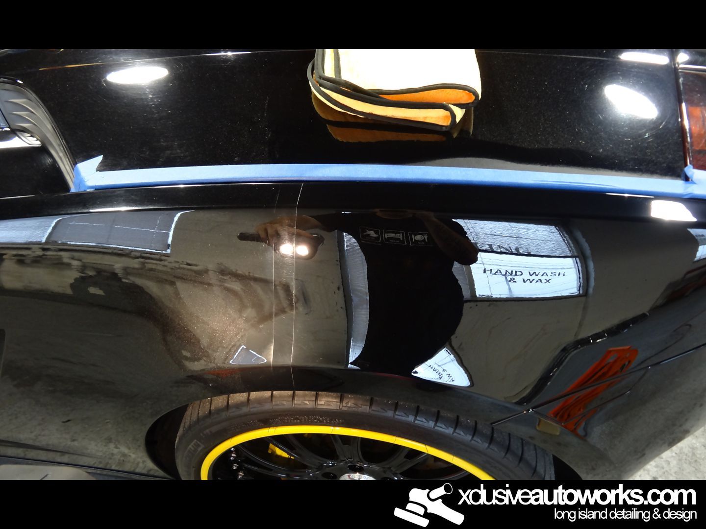 A black car is being polished by xclusiveautoworks.com