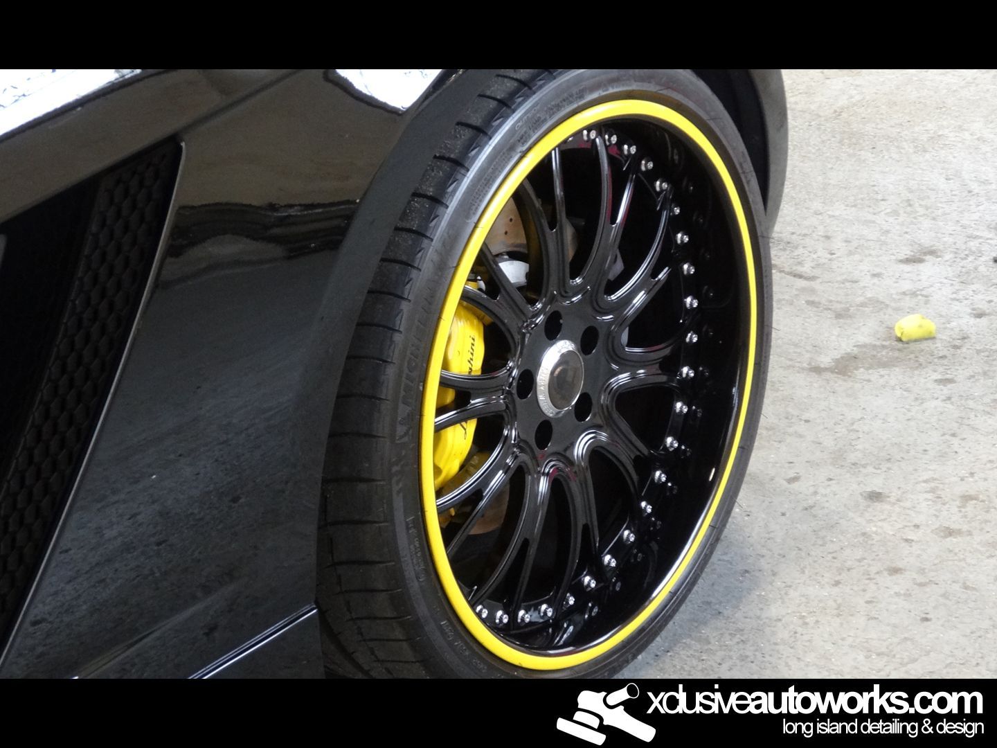 A close up of a black car wheel with yellow rims