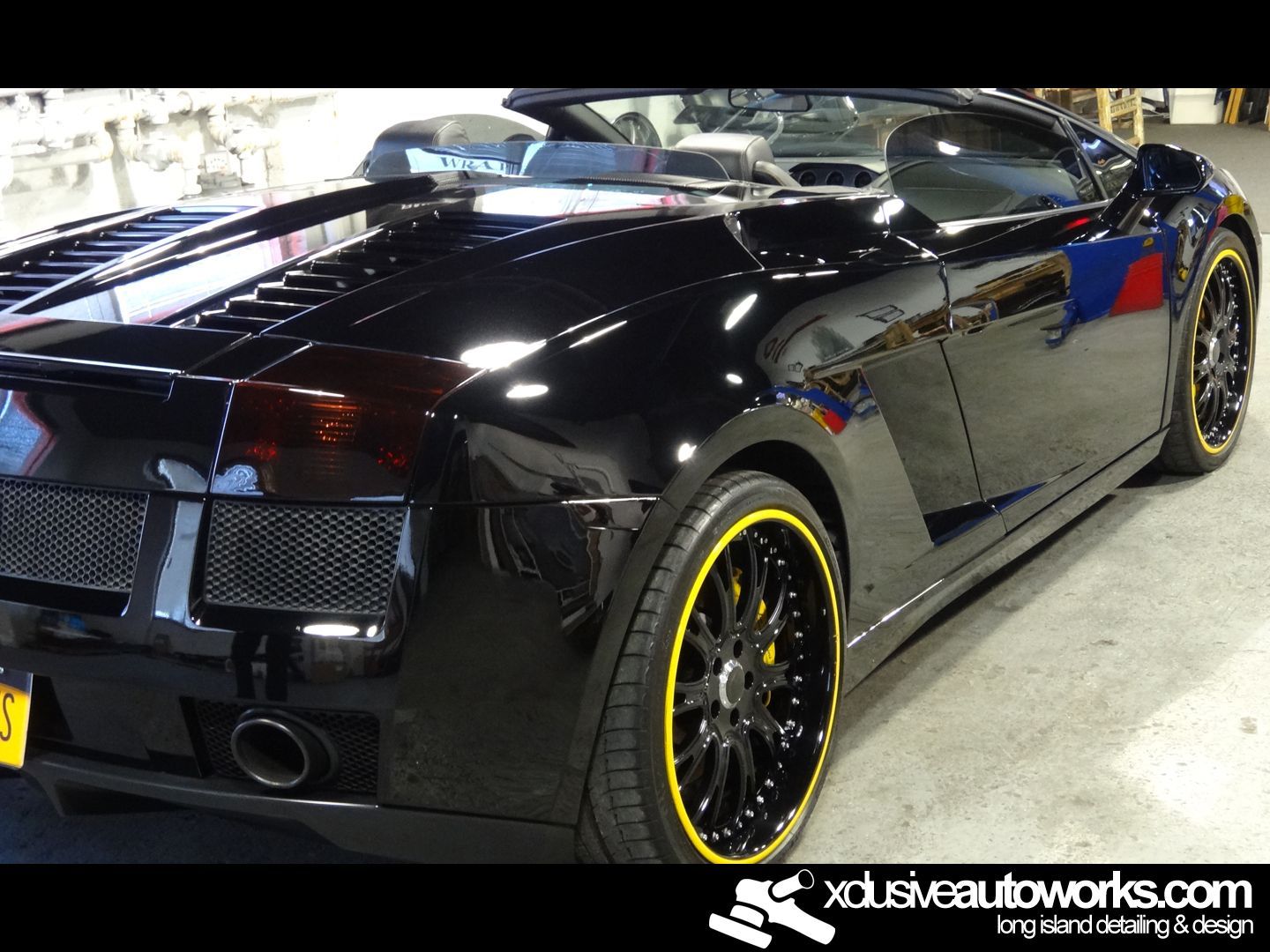 A black sports car with yellow rims is displayed on xdusveautoworks.com
