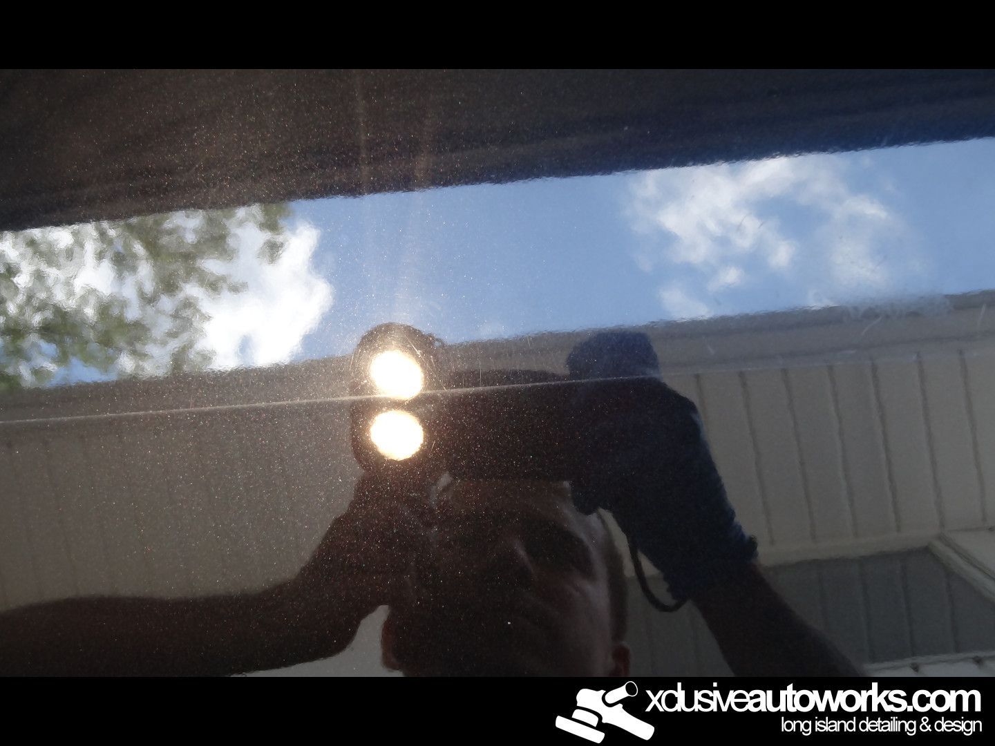 A person is taking a picture of a car with xdusveautoworks.com written on the bottom