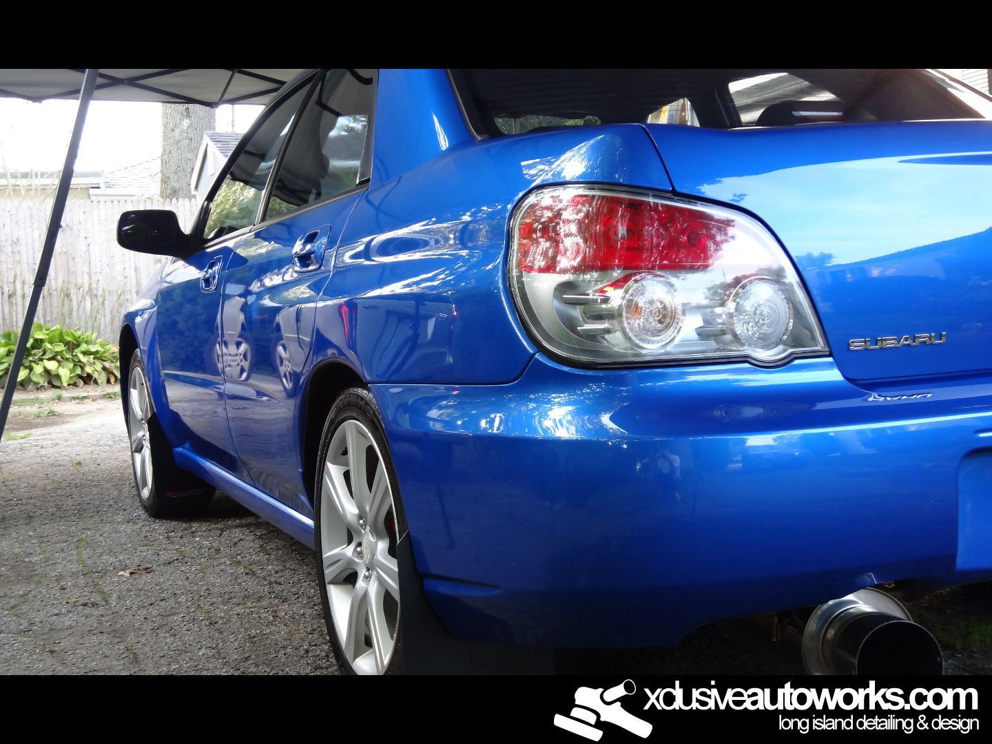 A blue subaru is parked in front of a tent