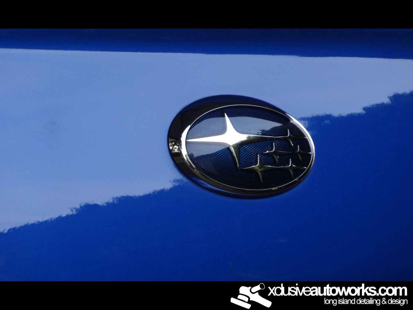 A subaru emblem is on the back of a blue car