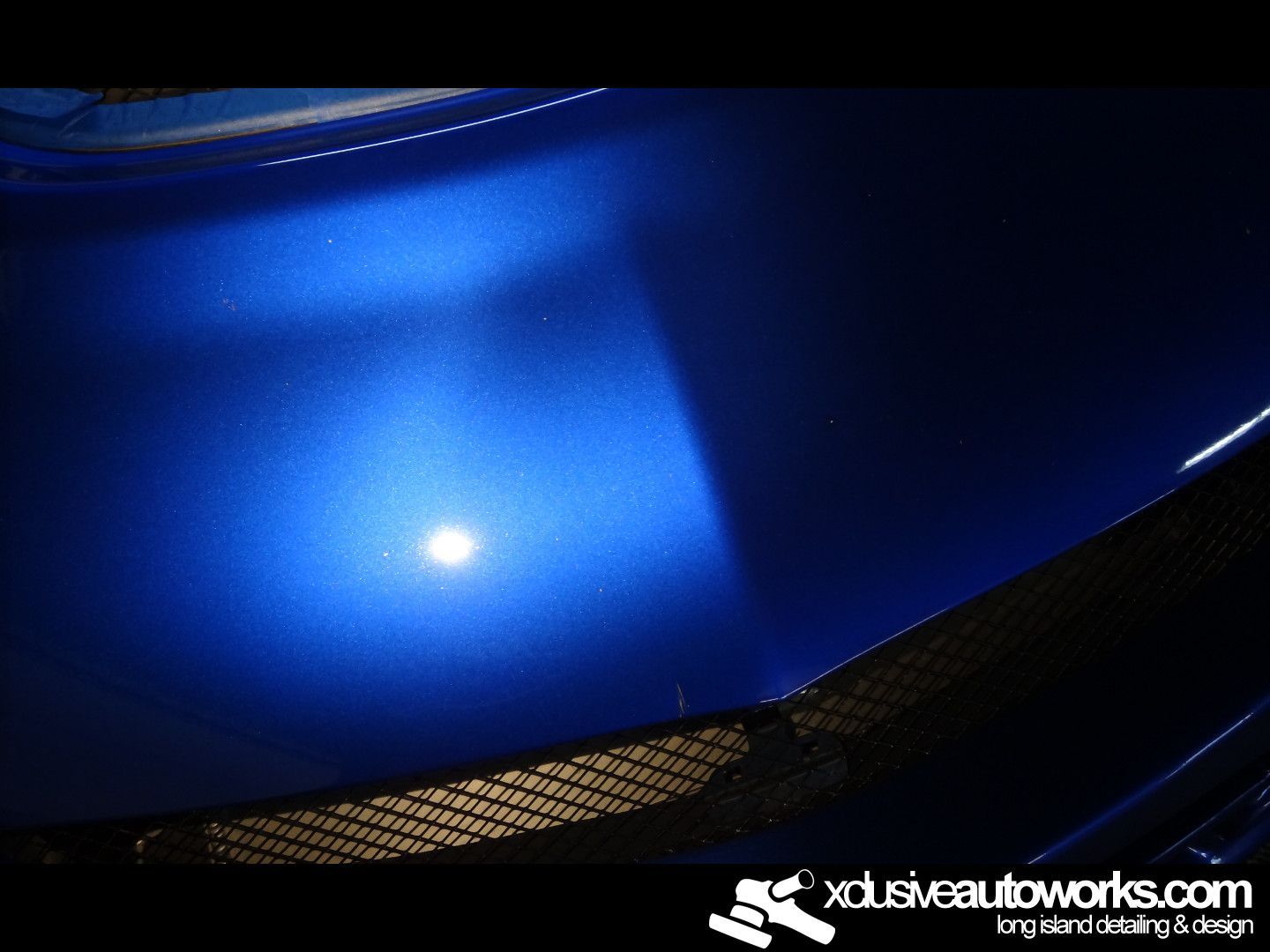 A close up of a blue car with xdusveautoworks.com written on the bottom