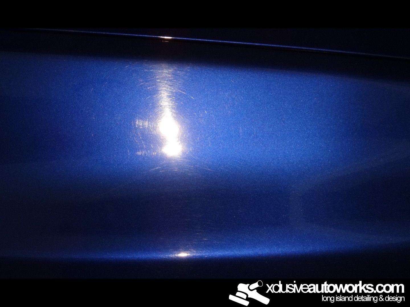 A close up of a blue car with xclusiveautoworks.com written on the bottom