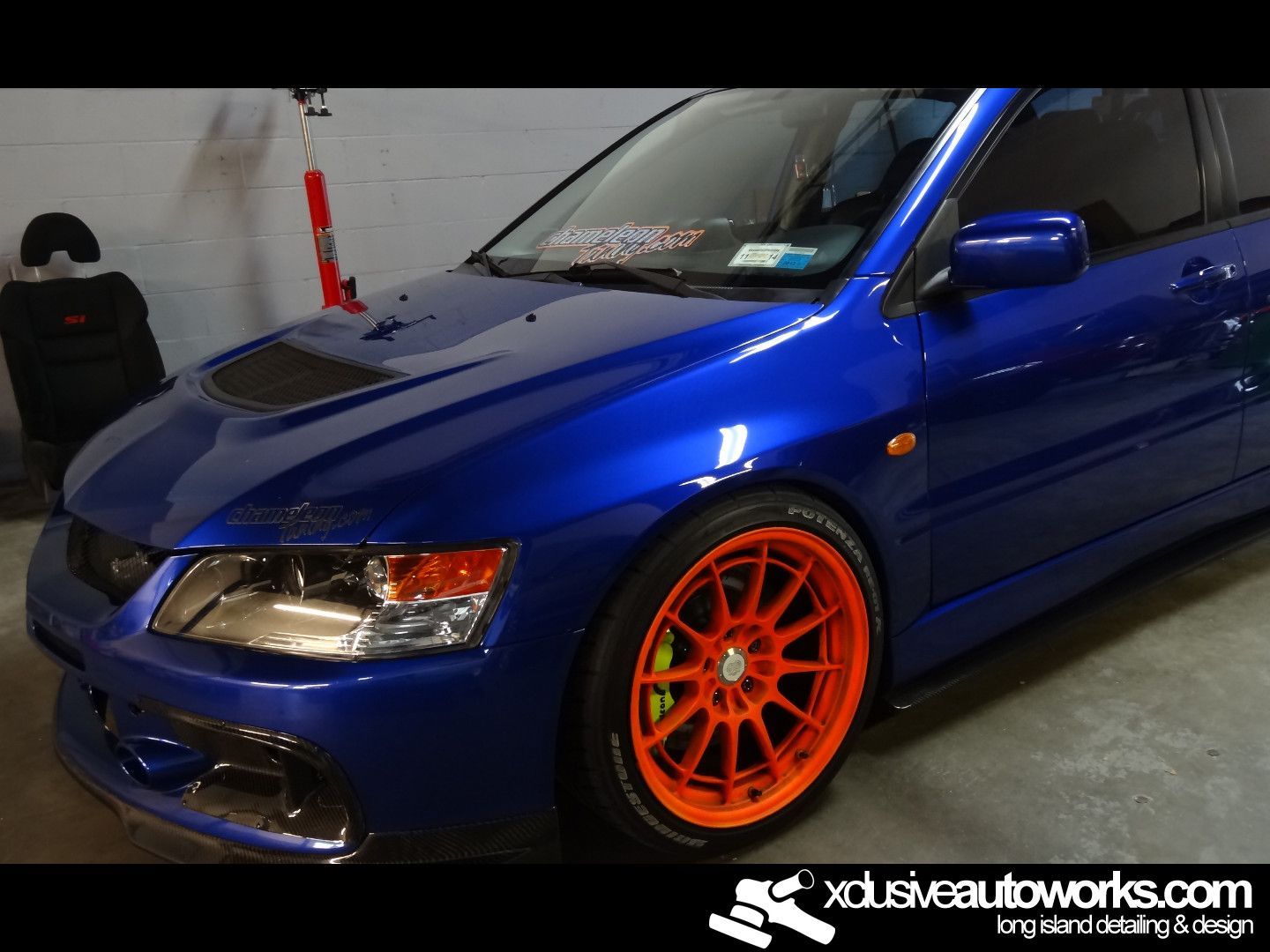 A blue car with orange wheels is parked in a garage