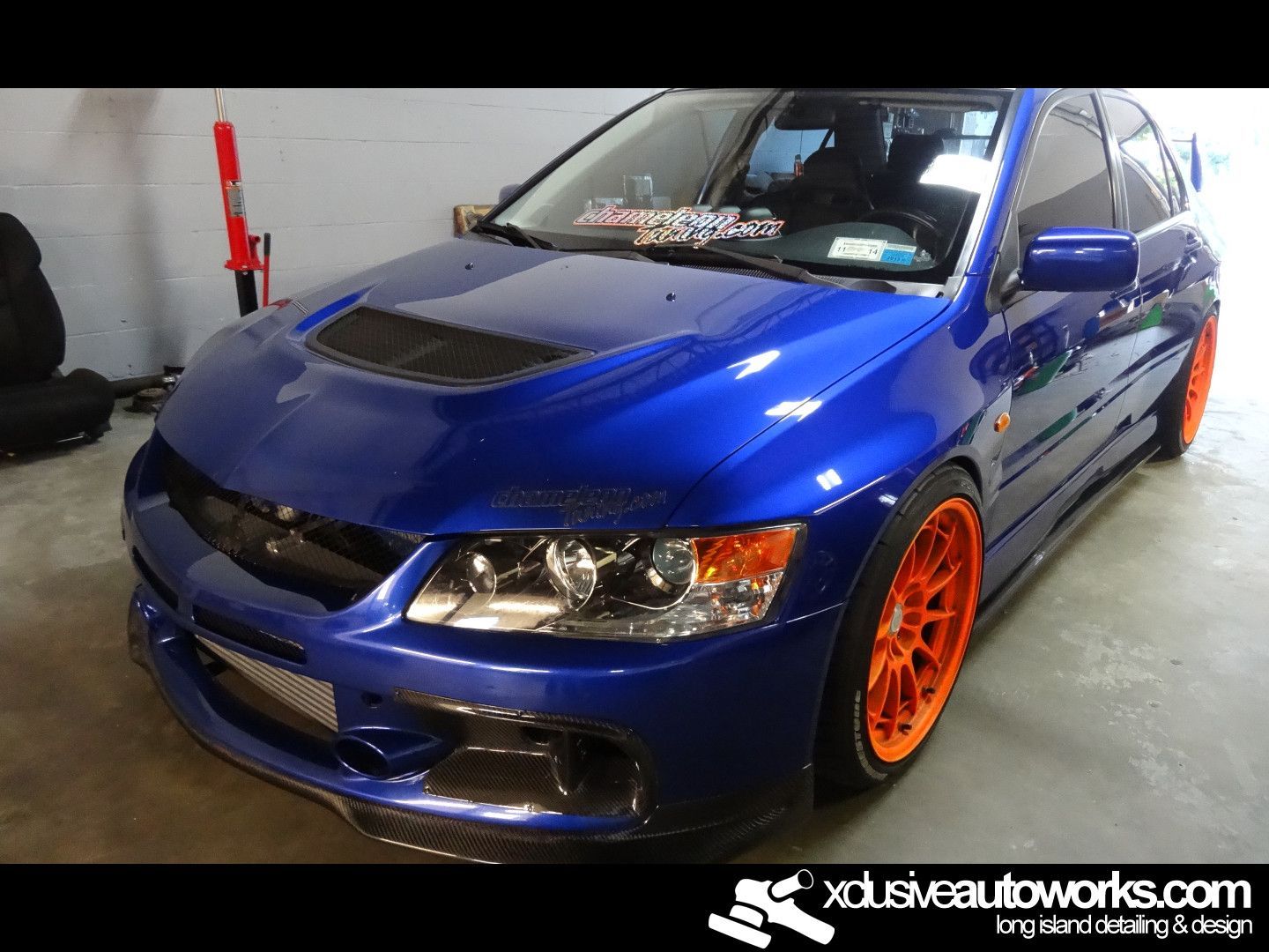 A blue car with orange wheels is parked in a garage