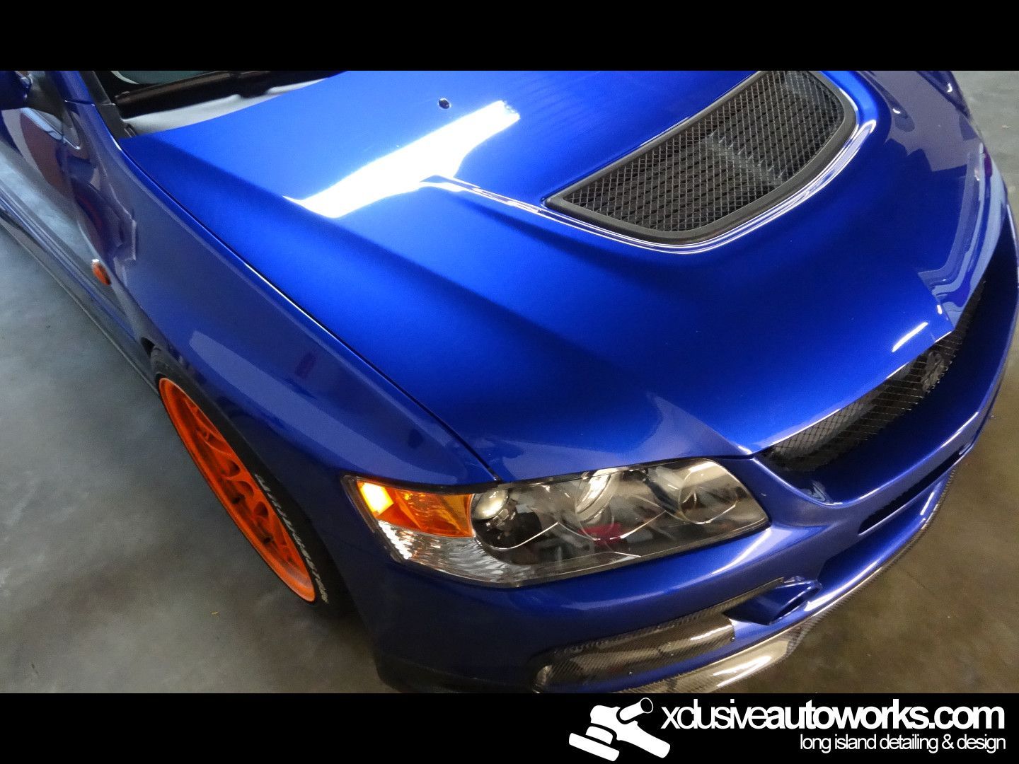 A close up of a blue car with xdusveautoworks.com written on the bottom