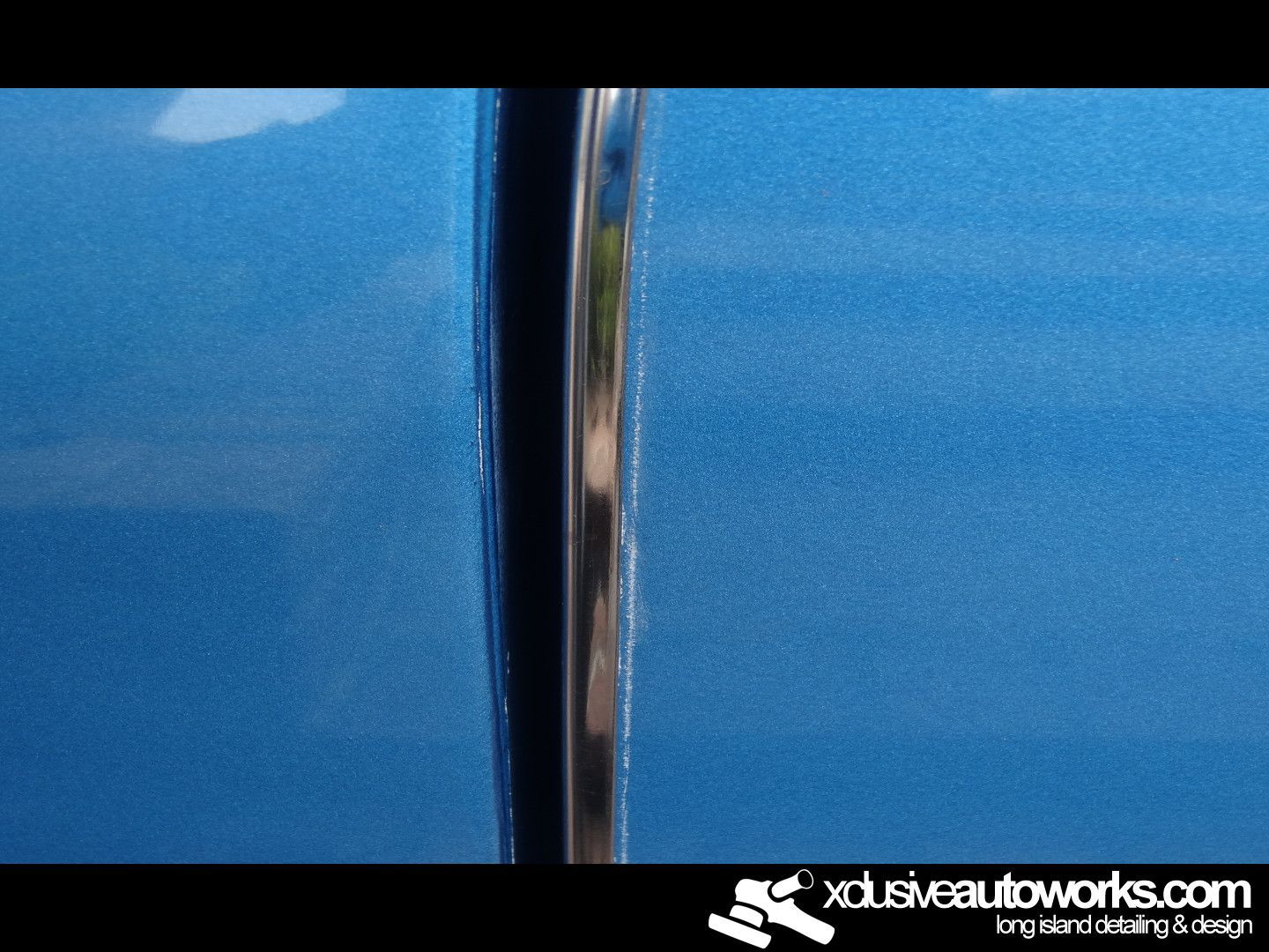 A close up of a blue car with xclusiveautoworks.com written on the bottom