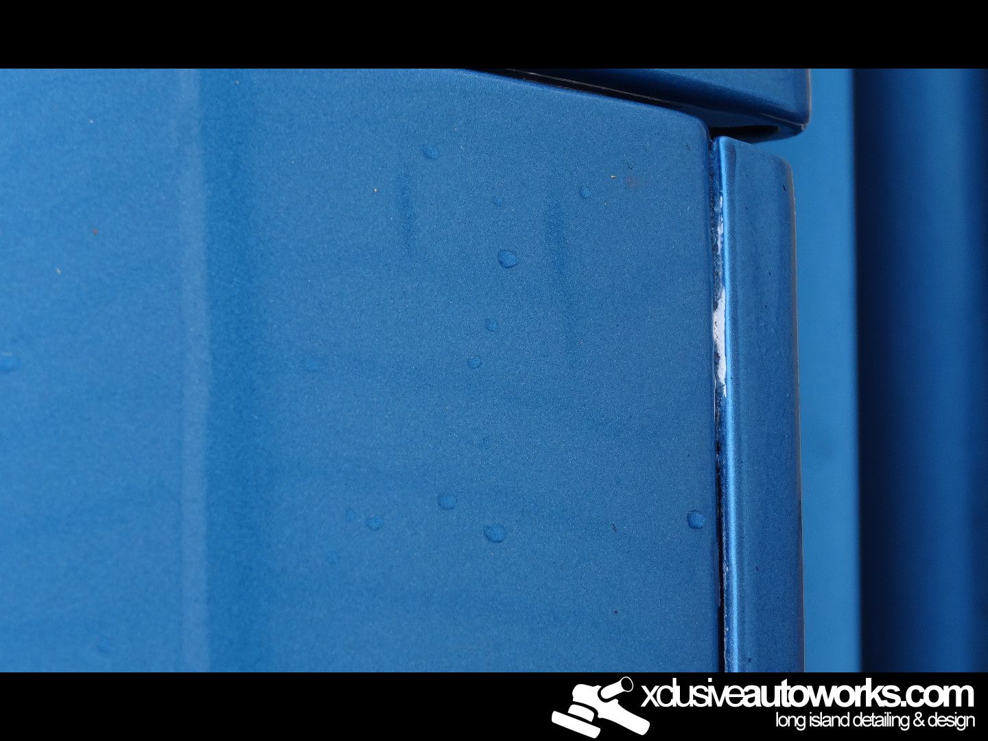 A blue wall with xclusiveautoworks.com written on the bottom