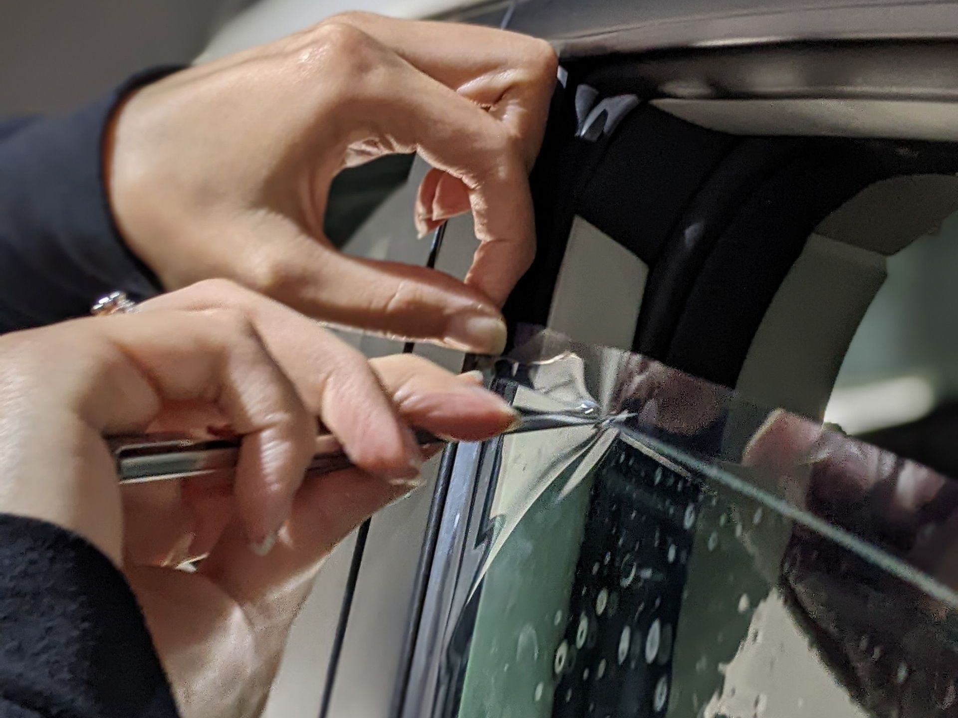 A person is cutting a piece of glass with a pair of scissors.