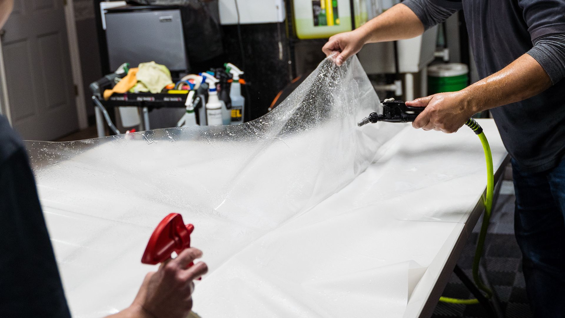 A man is cleaning the hood of a black car with a cloth.