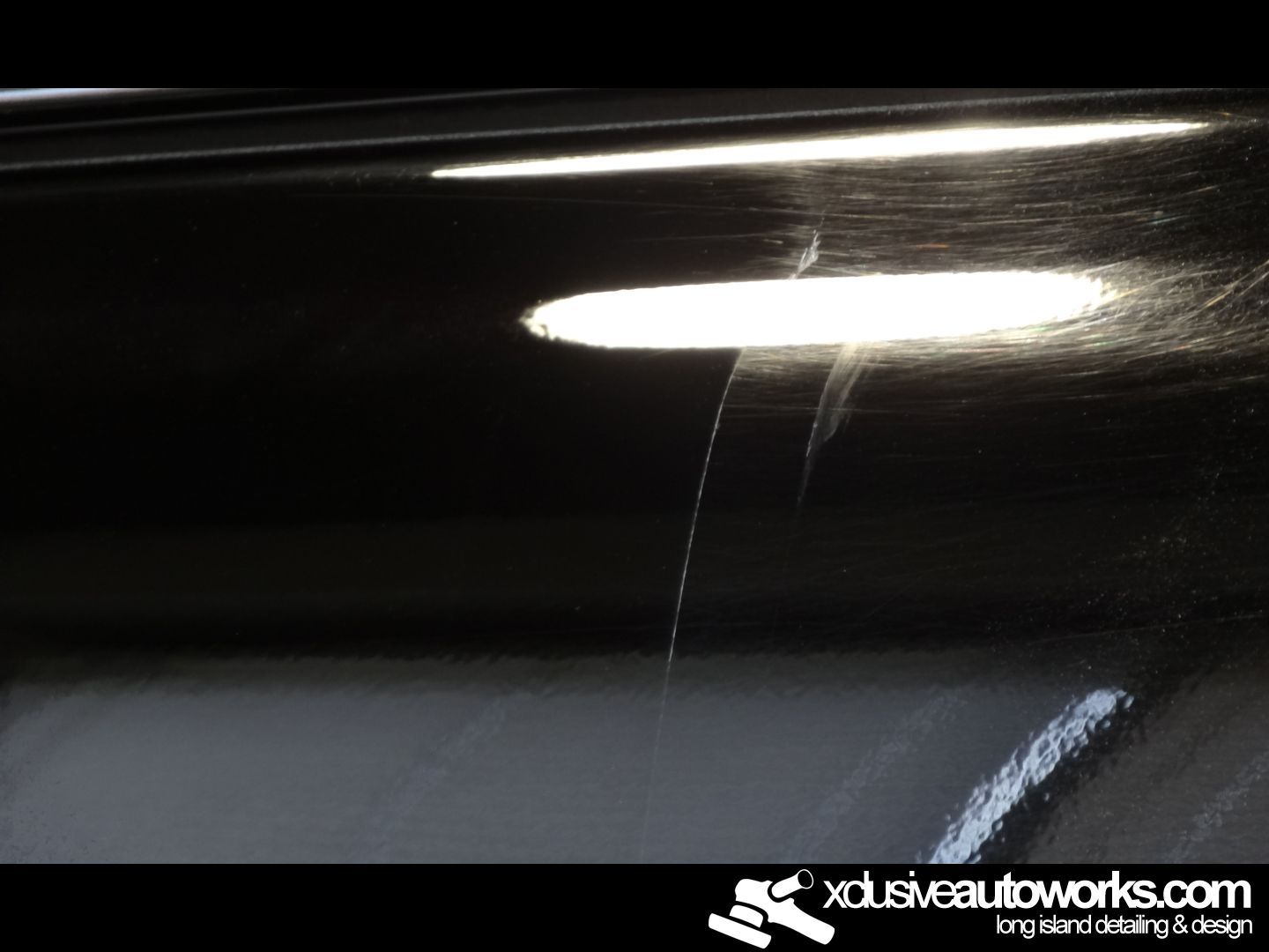 A close up of a black car with xclusiveautoworks.com written on the bottom