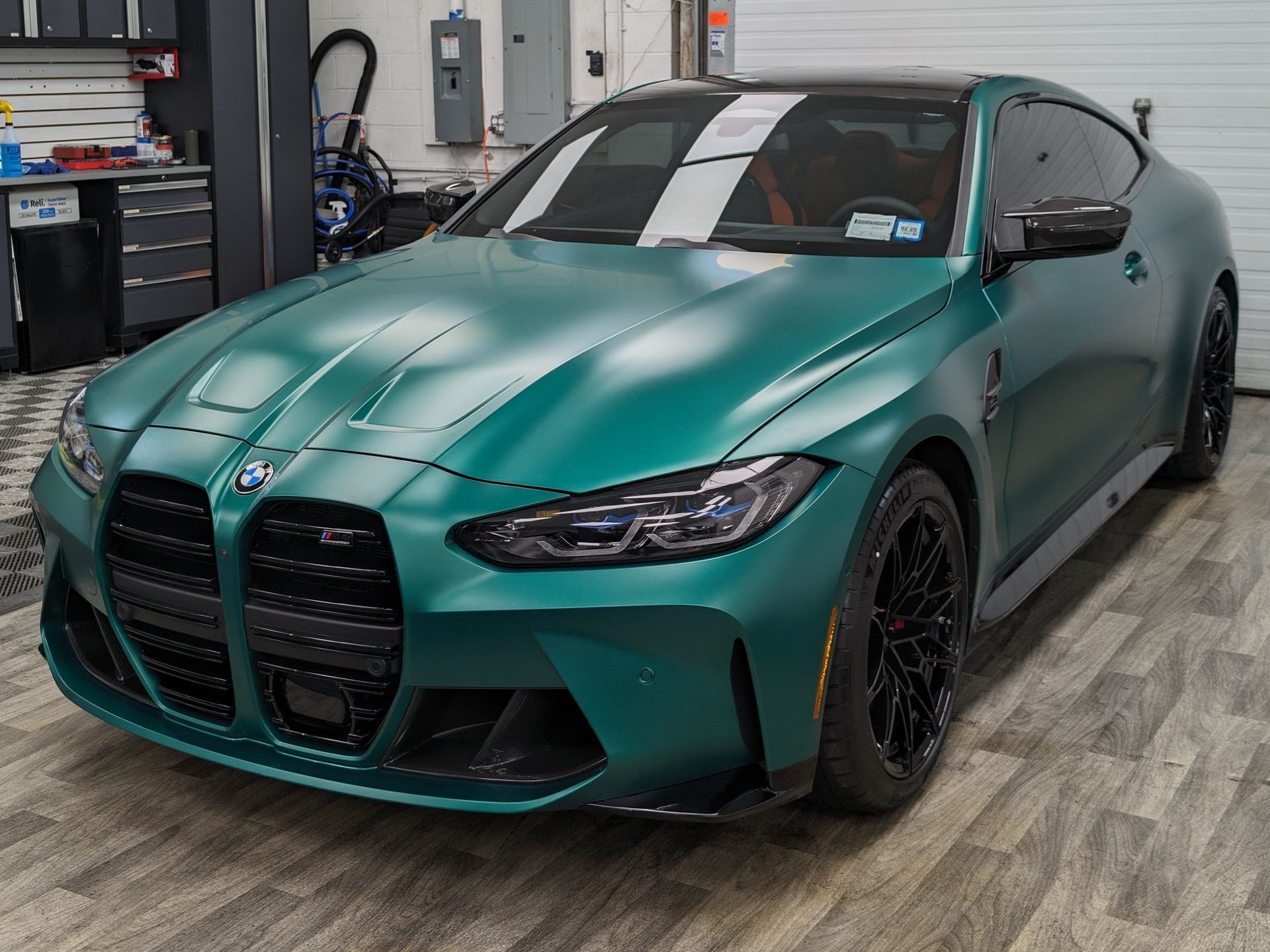 A green bmw m4 is parked in a garage.