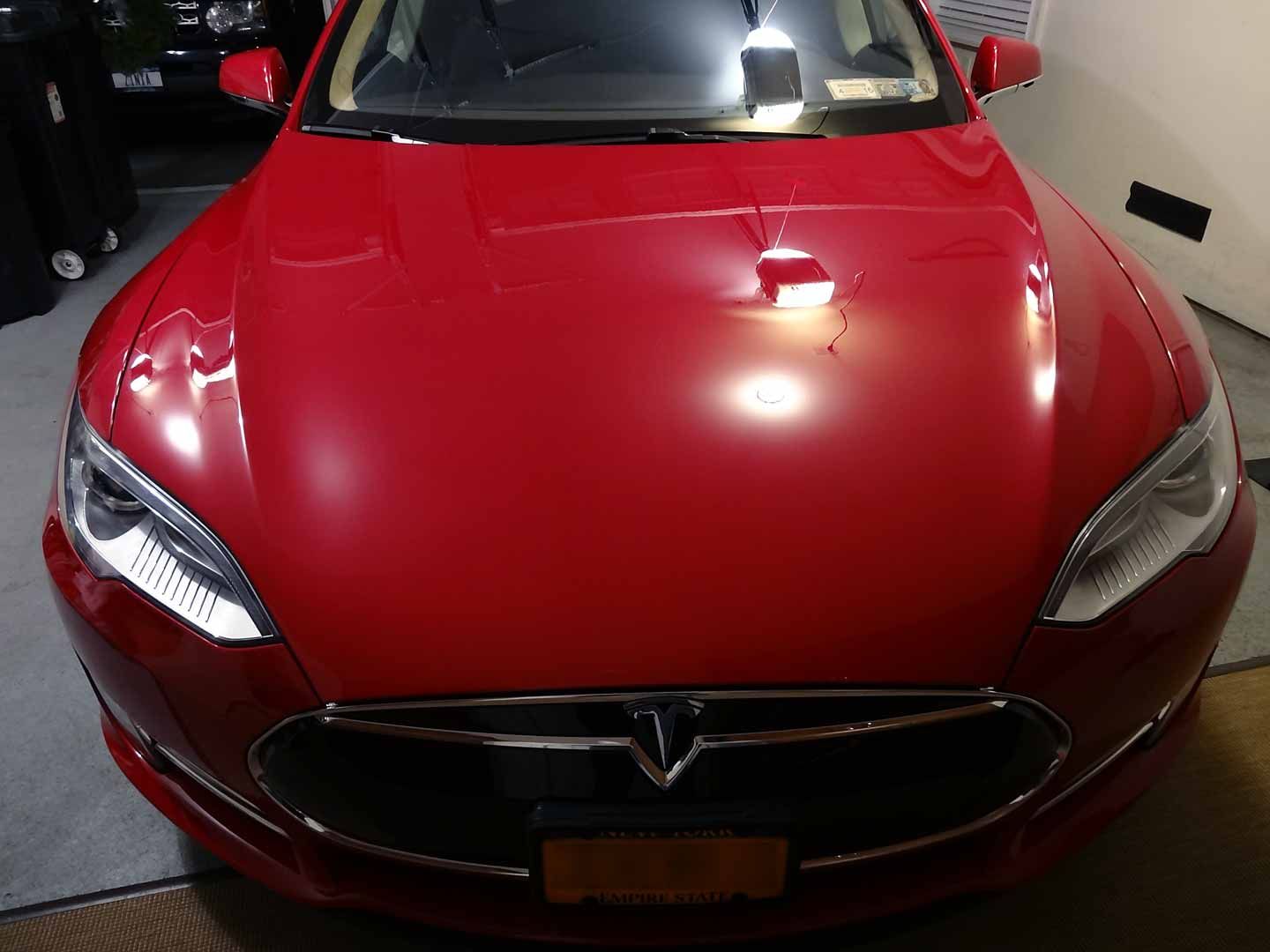 A red tesla model s is parked in a garage