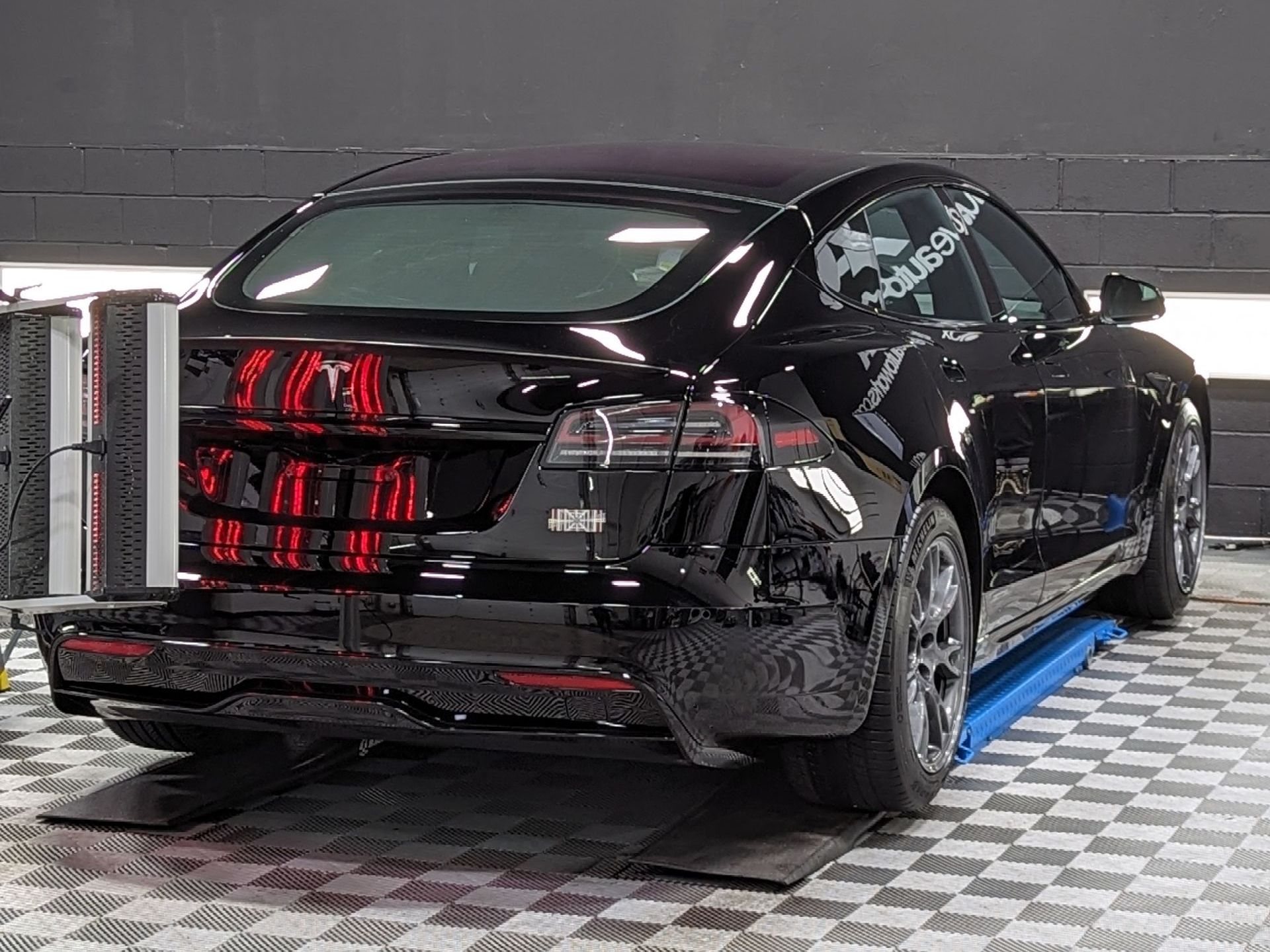 A man is cleaning the hood of a black car with a cloth.