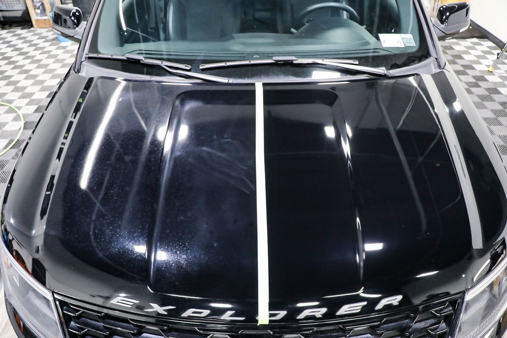 A black ford explorer is parked in a showroom with a checkered floor.