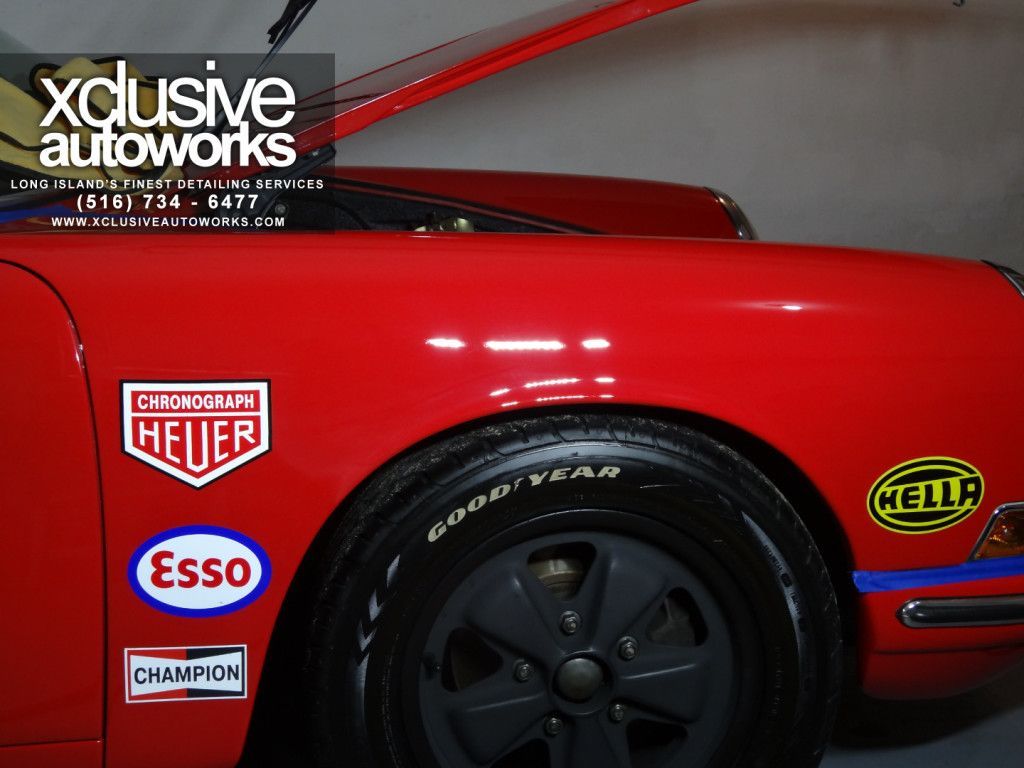 A red car with a sticker that says ' xclusive autoworks ' on it