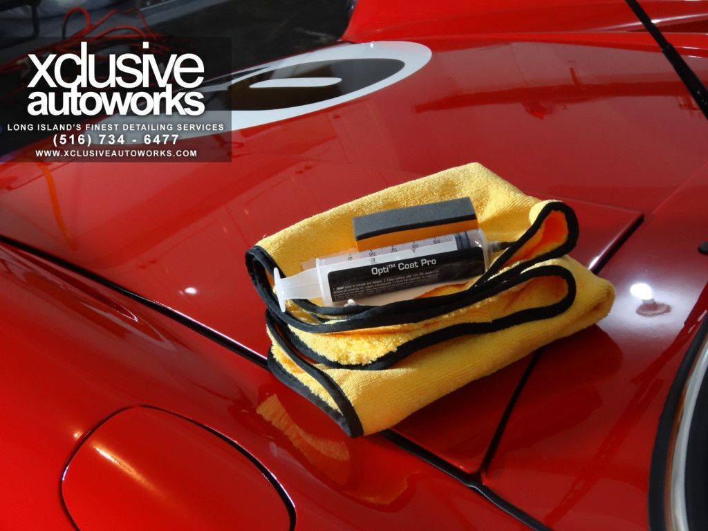 A yellow towel is sitting on the hood of a red car ..