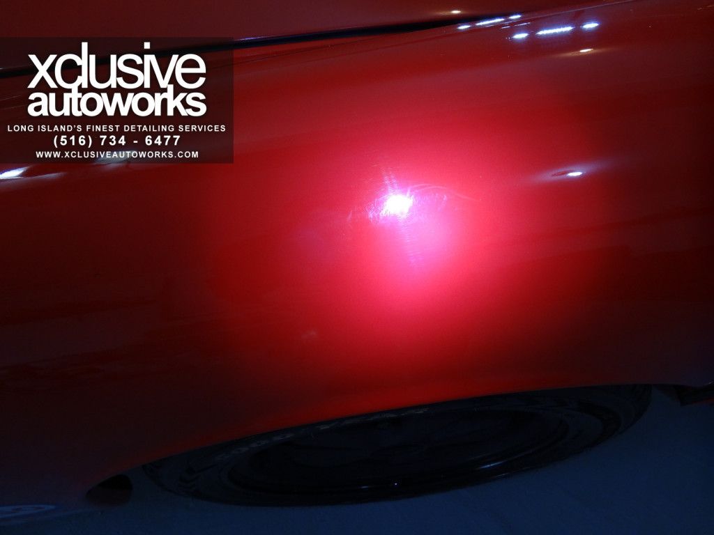 A close up of a red car with xclusive autoworks written on it